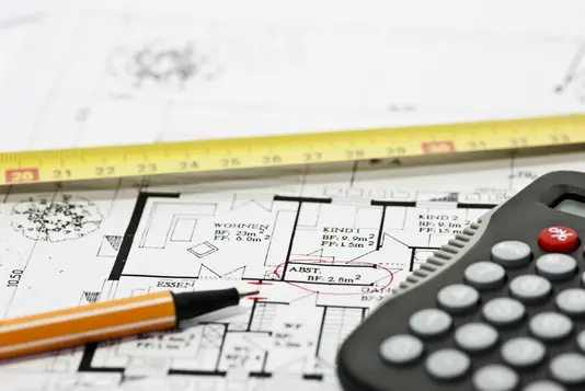 Bauplan mit Stift und Rechner